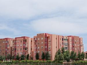 a large brick building with trees in front of it at Ennakhail apart in Marrakech