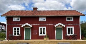 a red house with white windows and green doors at Brygghuset in Skillingaryd