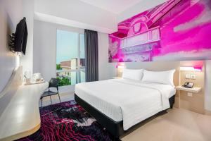 Una habitación de hotel con una cama blanca y un cuadro rosa. en favehotel Tuban, en Tuban 30 fotos más