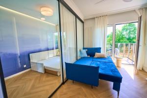 a bedroom with a blue bed and a balcony at BLISKO Plaży in Gdańsk