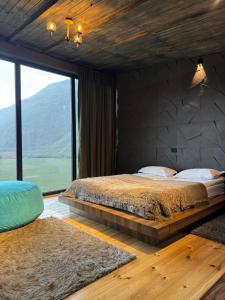 una camera da letto con un letto grande e una grande finestra di Gzaze a Kazbegi