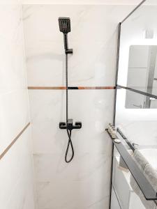 a shower in a white bathroom with a black shower head at Royal Wellness Apartman in Hévíz +7 photos