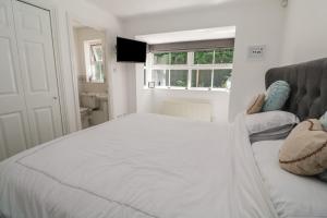 a bedroom with a large white bed and a television at Jaluna in St Ives
