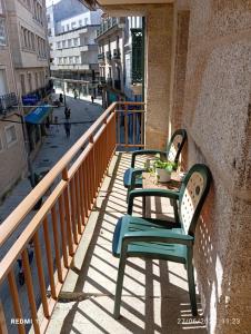 a table and chairs on a balcony with a street at Casa de piedra céntrica. in Ribeira
