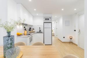 a kitchen with white cabinets and a table with a vase at Sun Duplex in Fuengirola