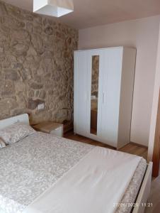 a bedroom with a bed and a stone wall at Casa de piedra céntrica. in Ribeira