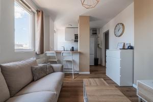 a living room with a couch and a kitchen at L'Escapade Strasbourgeoise - Magnifique petit T2 refait à neuf in Strasbourg