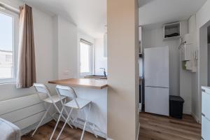 a small kitchen with a counter and chairs in a room at L'Escapade Strasbourgeoise - Magnifique petit T2 refait à neuf in Strasbourg +3 photos