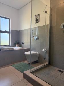 a bathroom with a shower and a toilet and a tub at Stylish Ballito Home - Zimbali Wedge in Ballito