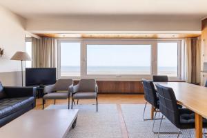 Una sala de estar con una mesa y sillas y una gran ventana. en Clapotis A 0701 G, en Oostduinkerke