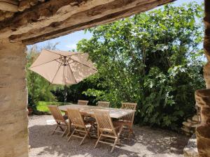 una mesa de madera con sillas y una sombrilla en Restored 18Th Century Farmhouse Near Albi, en Rouffiac
