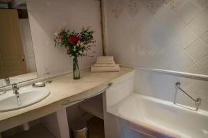 Un baño con un lavabo y un jarrón de flores. en Restored 18Th Century Farmhouse Near Albi, en Rouffiac