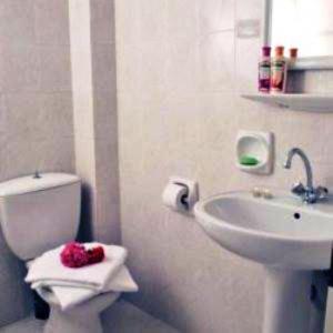 a white bathroom with a toilet and a sink at Saint George Hotel in Rodakino