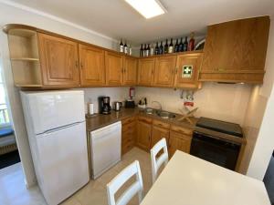 a kitchen with wooden cabinets and a white refrigerator at Casa Melli with Sunset Oceanview Terrace in Lourinhã