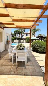 a patio with a white table and white chairs at Villa Porta Aurea in Ayia Napa