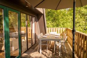 a wooden deck with a table and an umbrella at Hidden jewel in Durbuy's forest in Durbuy