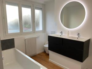 a bathroom with a tub and a sink and a mirror at Maison lumineuse avec jardin & parking clos in Cucq +15 photos