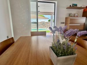 a vase of purple flowers sitting on a wooden table at Modern 3-Bedroom Villa with Private Pool & BBQ in Cádiz