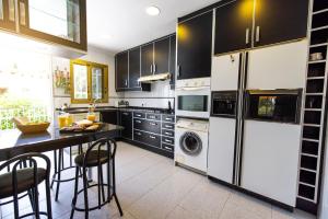 una cocina con armarios negros, lavadora y secadora en Oasis Salou, en Salou