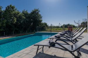 a row of lounge chairs next to a swimming pool at E&M Forest Retreat in Svetvinčenat