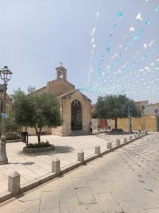 eine Kirche mit einem Gebäude im Hintergrund mit Gebetsfahnen in der Unterkunft Loft di Gianluca e Grazia in Maracalagonis