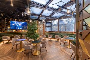 ein Restaurant mit Tischen und Stühlen in einem Raum mit Fenstern in der Unterkunft Castelnor in Păltiniş