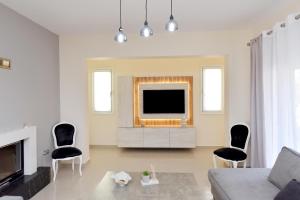 a living room with a television and two chairs at Seraina House in Pastida