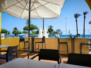 a restaurant with chairs and tables and an umbrella at Tu lugar feliz al lado del mar in Mazarrón