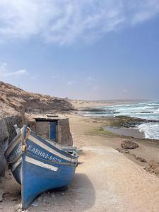 a blue boat sitting on the shore of a beach at Eco Stay by Ocean Sea View Apartment near Souss Massa National Park in Rbat