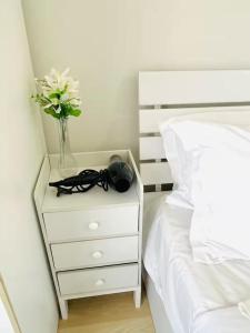 a vase of flowers on a night stand next to a bed at Xin Hostel Wachiratham 21 in Amphoe Phra Khanong +21 photos