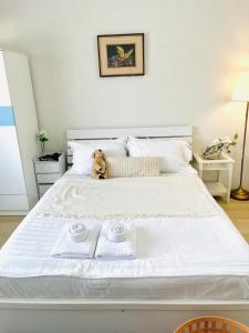 a teddy bear sitting on a bed with two towels at Xin Hostel Wachiratham 21 in Amphoe Phra Khanong
