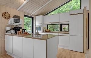 a kitchen with white cabinets and a large window at Holiday Home Højdevej in Vejby