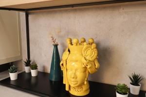 a yellow statue sitting on a table with plants at Appartamenti centro città Downtown Aitne in Catania +15 photos