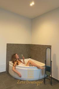 a woman sitting in a bath tub with a bottle at Zeta Boutique in Caserta +117 photos