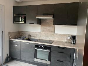 a kitchen with stainless steel appliances and black cabinets at Maison spacieuse et agréable à 200m de la mer in Saint-Nazaire