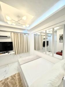 a white living room with a tv and a couch at Budget Loft-type condo in Uptown CDO in Cagayan de Oro