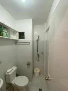 a white bathroom with a toilet and a shower at Budget Loft-type condo in Uptown CDO in Cagayan de Oro +20 photos