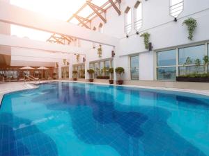 a large swimming pool with blue water in a building at Grand Mercure Majlis Residences in Abu Dhabi