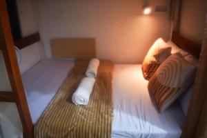 a small room with a bunk bed with white sheets at Bolo Airport Dormitel in Mactan Cebu International