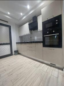a kitchen with white cabinets and black appliances at Appartement à Khezama Est Sousse in Hammam Sousse