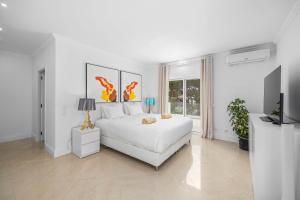 a white bedroom with a white bed and a tv at Vale Do Lobo Resort in Vale do Lobo