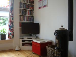 een woonkamer met een tv en een plank met dvd's bij B&B Hotel California in Wichmond