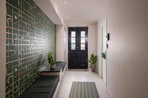 a hallway with a black door and green tiles at Living Yard Thissio in Athens