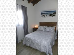 Un dormitorio con una cama con un edredón blanco. en Casa El Duque Leire, en Vejer de la Frontera