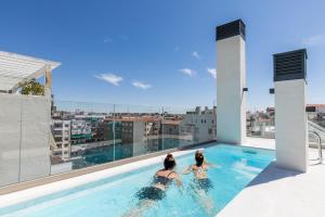 dwie kobiety w basenie na dachu budynku w obiekcie Feelathome Goya Apartments w Madrycie