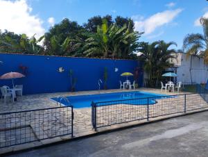a pool with tables and chairs and a blue wall at pousada recanto do coelho in Roseira