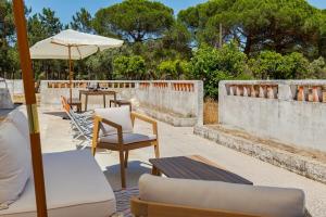 a patio with a table and chairs and an umbrella at Comporta Serenity Villa in Grândola