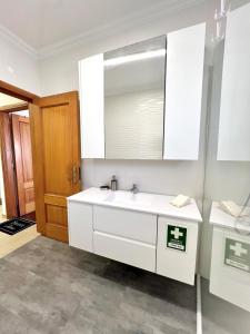 a white bathroom with a sink and a mirror at O caminho da praia in Bicas