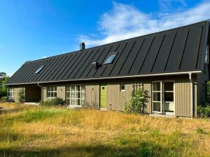 a house with a black roof on a field at Modern Family Home In Ängelsbäcksstrand in Båstad