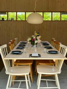 a dining room table with chairs and a large table with flowers at Modern Family Home In Ängelsbäcksstrand in Båstad +19 photos
